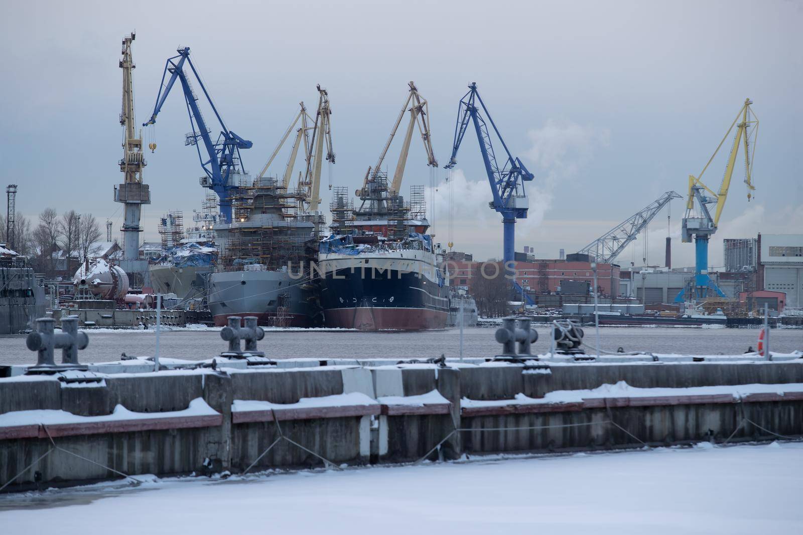 The construction of nuclear icebreakers, cranes of of the Baltic shipyard in a frosty winter day, steam over the Neva river, smooth surface of the river. High quality photo