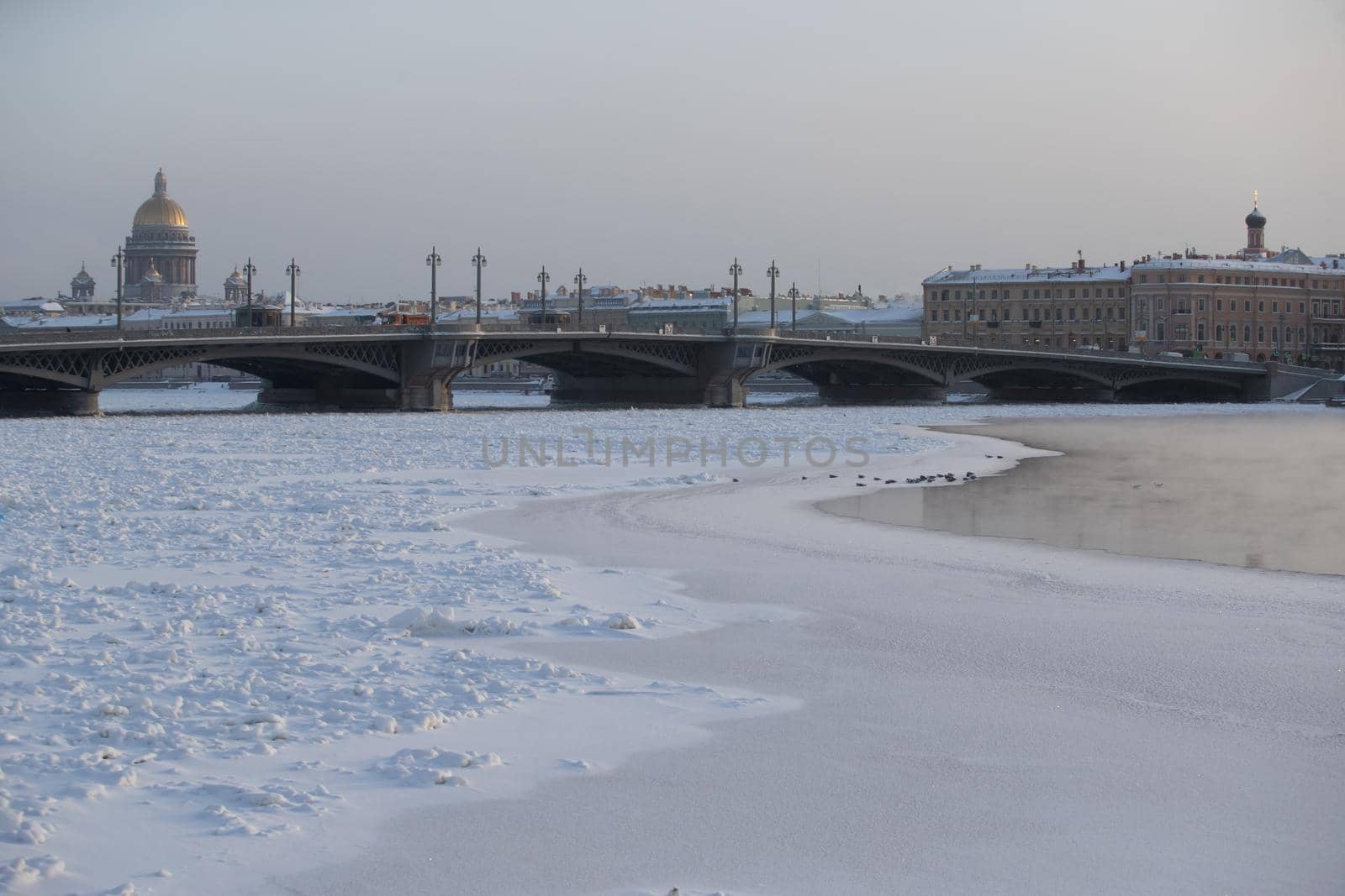 Winter panoramic view of St. Petersburg at frosty day, Isaac cathedral and Blagoveshenskiy bridge on background, steam over frozen Neva river. High quality photo