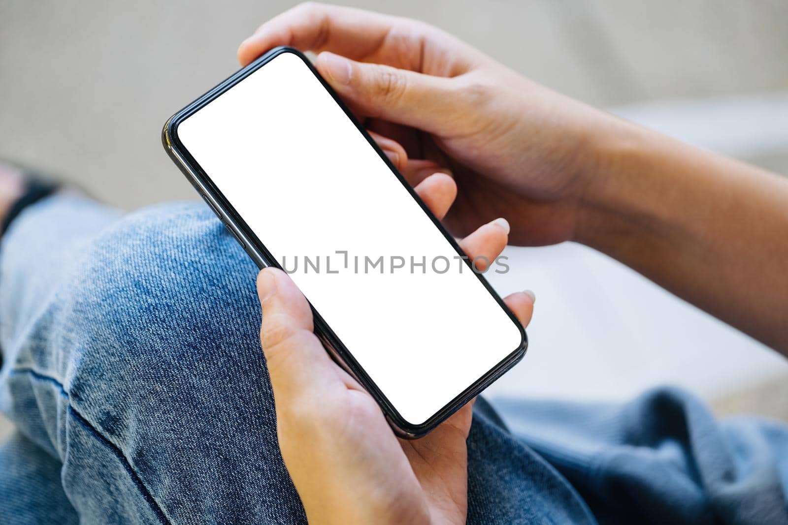 A woman holding a cell phone with a blank white screen. The blank space on the white screen can be used to write a message or place an image