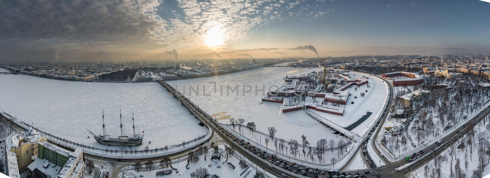 Drone point of view of winter St. Petersburg at sunset, frozen Neva river, steam over city, Peter and Paul fortress, car traffic on Trinity bridge, rostral columns, Palace drawbridge, panoramic view. High quality photo
