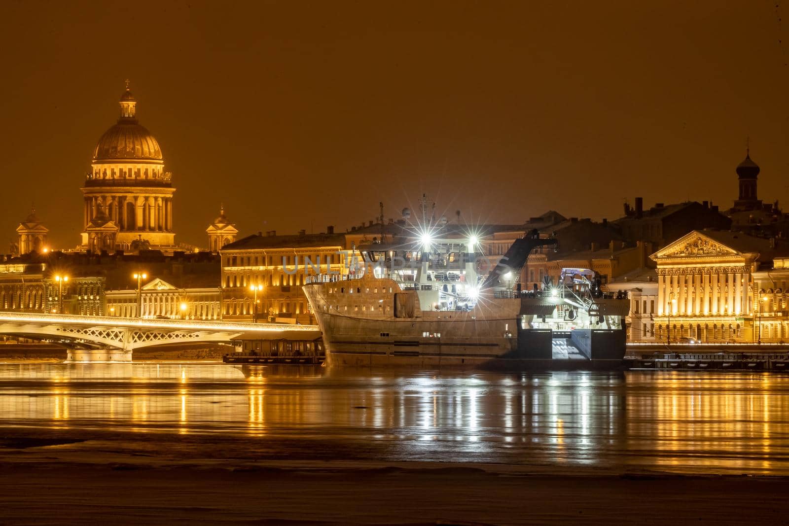 The panoramic footage of the winter night city Saint-Petersburg with picturesque reflection on water, big ship moored near Blagoveshchensky bridge or lieutenant Schmidt, Isaac cathedral on background. High quality photo