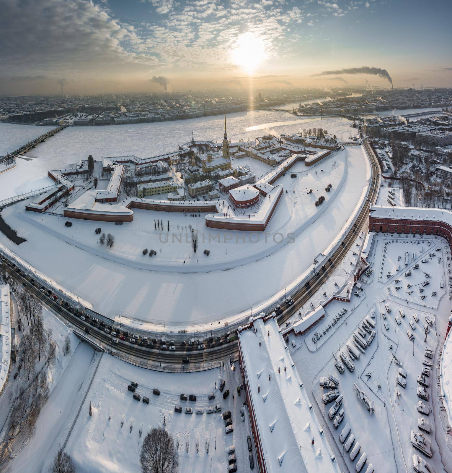 Drone point of view of winter St. Petersburg at sunset, frozen Neva river, steam over city, Peter and Paul fortress, car traffic on Trinity bridge, rostral columns, Palace drawbridge, panoramic view. High quality photo
