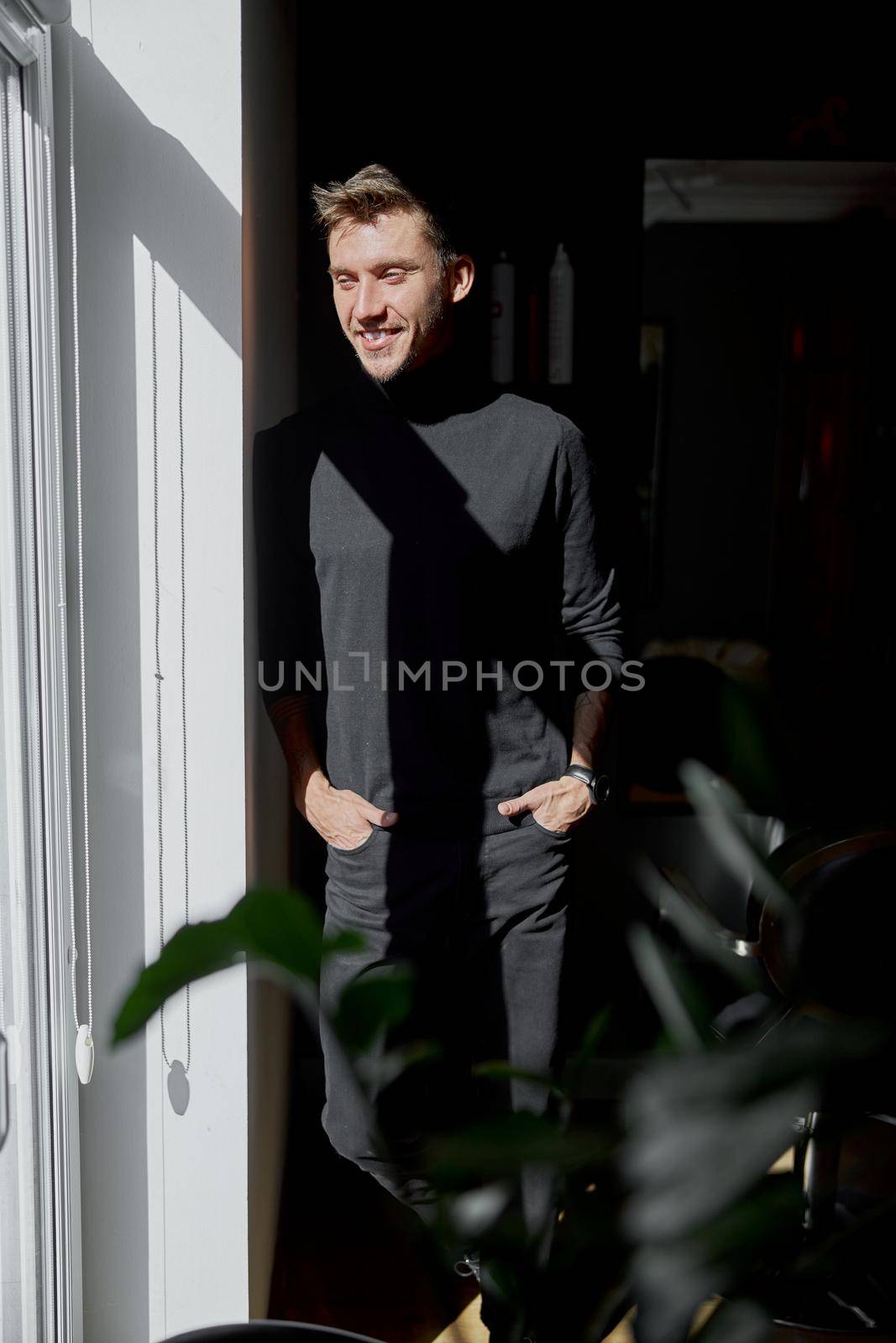 Male happy smiling hairdresser at his modern salon