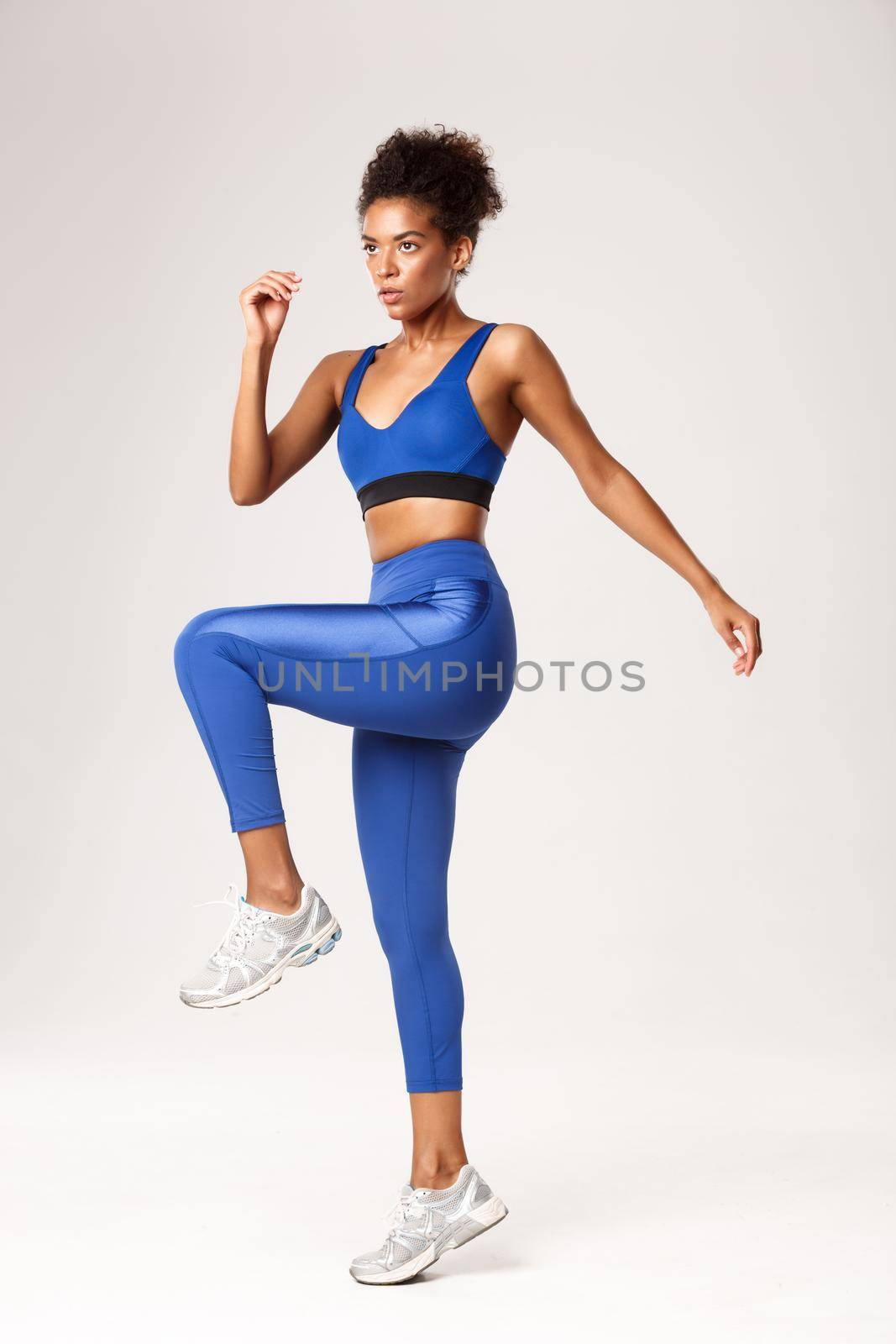 Full length of determined fitness girl in blue sportswear workout in gym, looking serious, standing over white background.