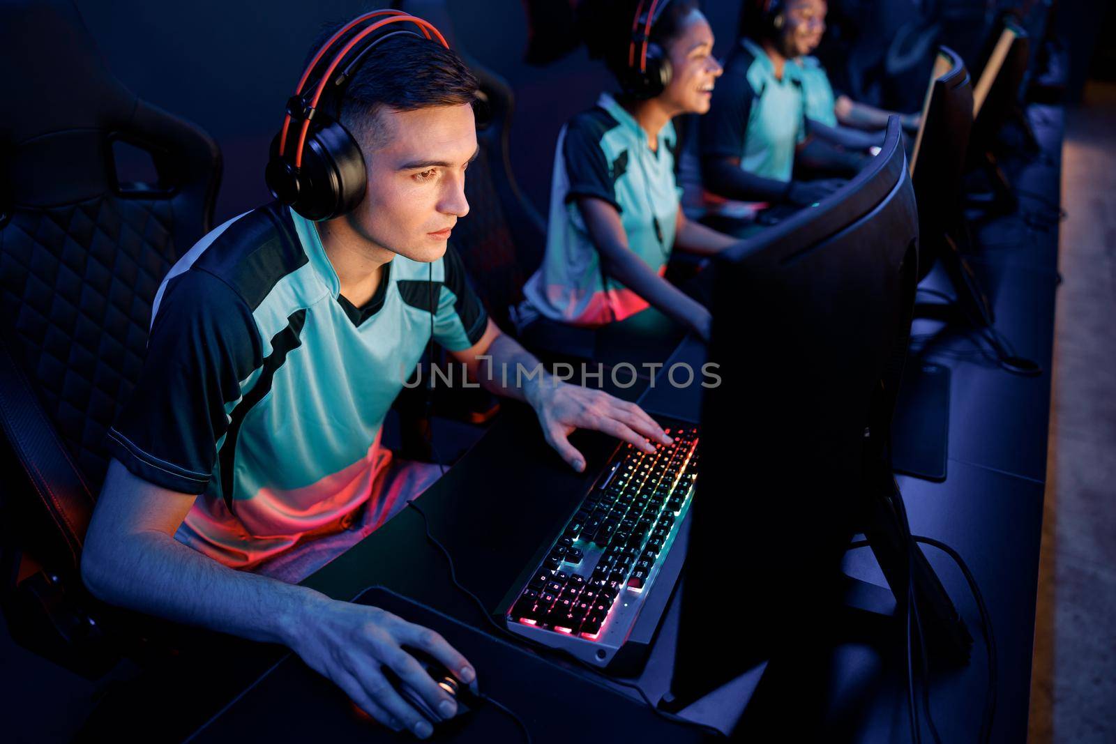Young esports player concentrated on game wearing wired headset while playing online multiplayer game in cyber club