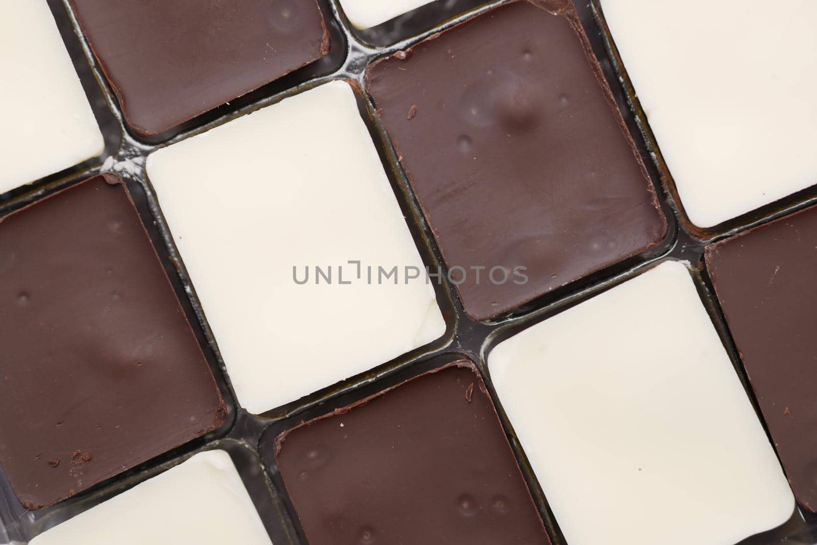 dark and white chocolate in a box on gray background .