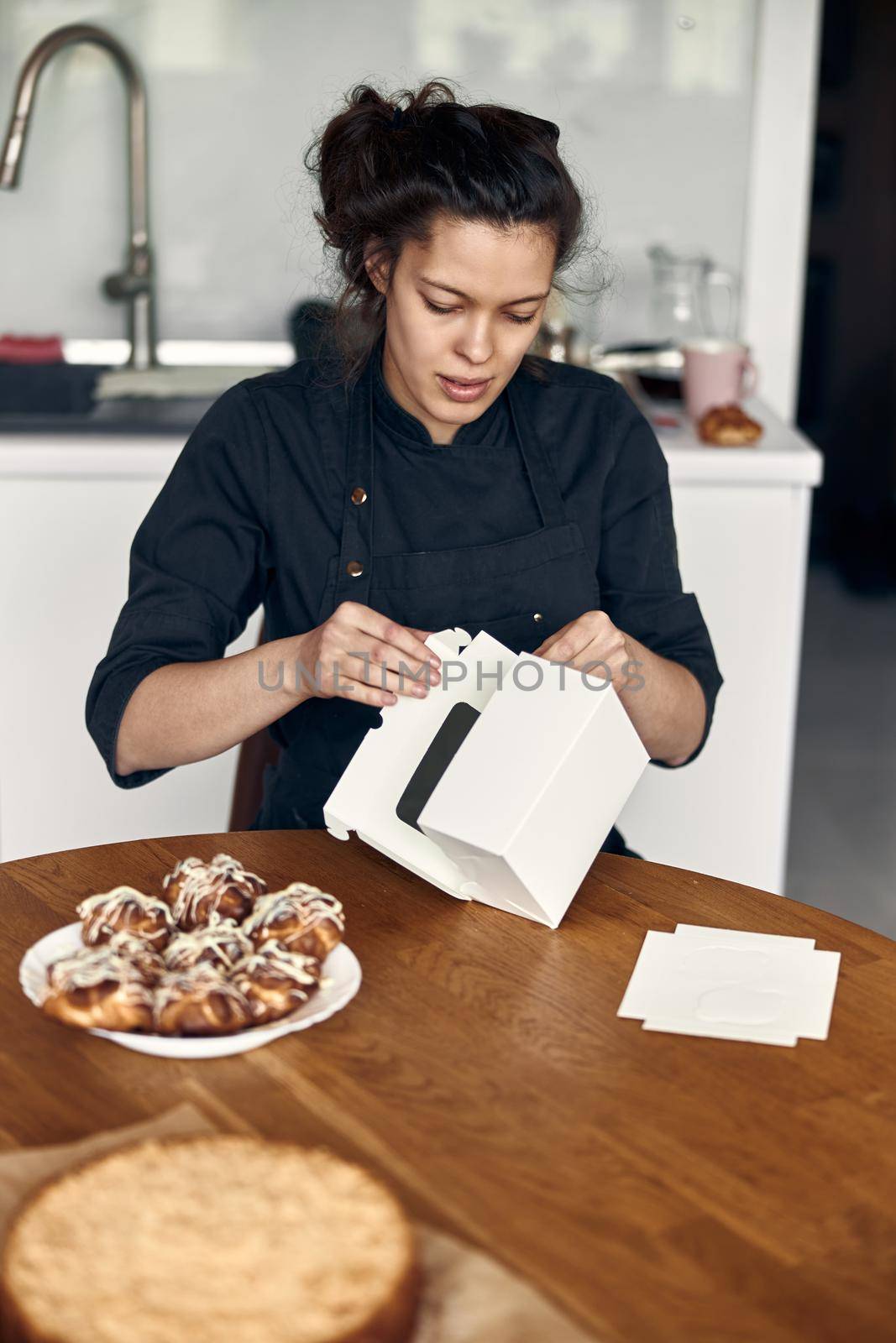 smiley woman is preparing tasty sweet dishes at light minimalistic kitchen