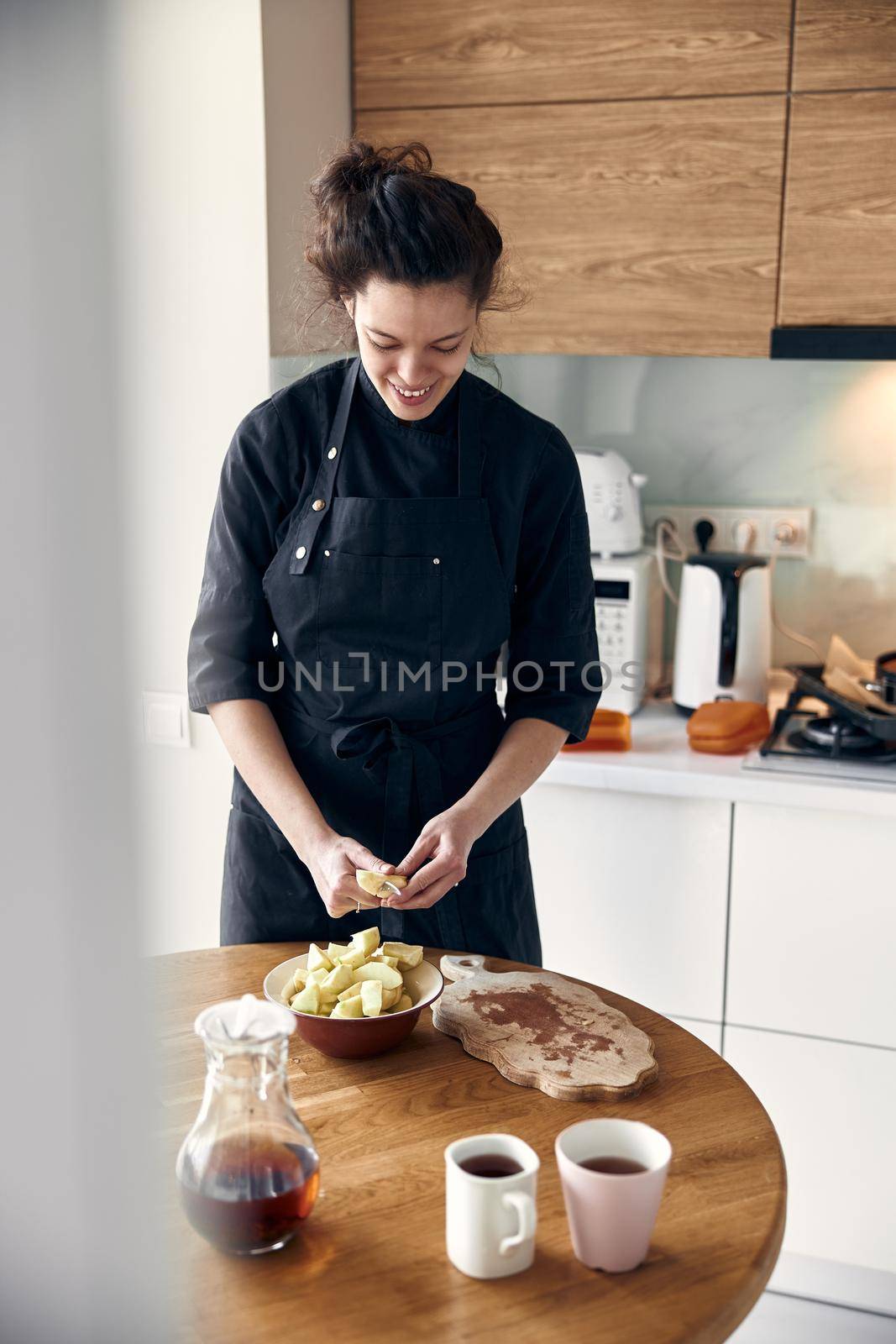 smiley woman is preparing tasty sweet dishes at light minimalistic kitchen