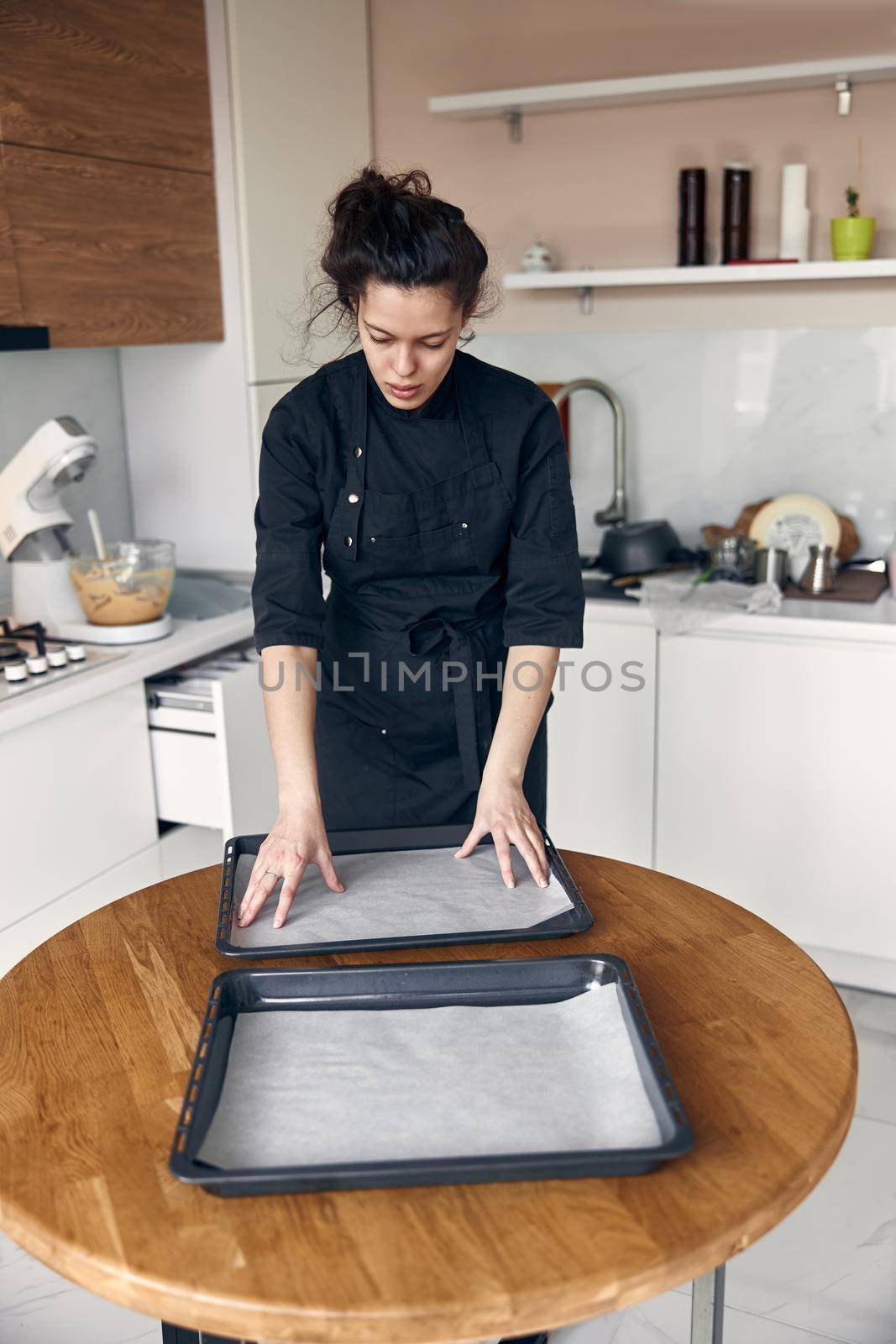 smiley woman is preparing tasty sweet dishes at light minimalistic kitchen