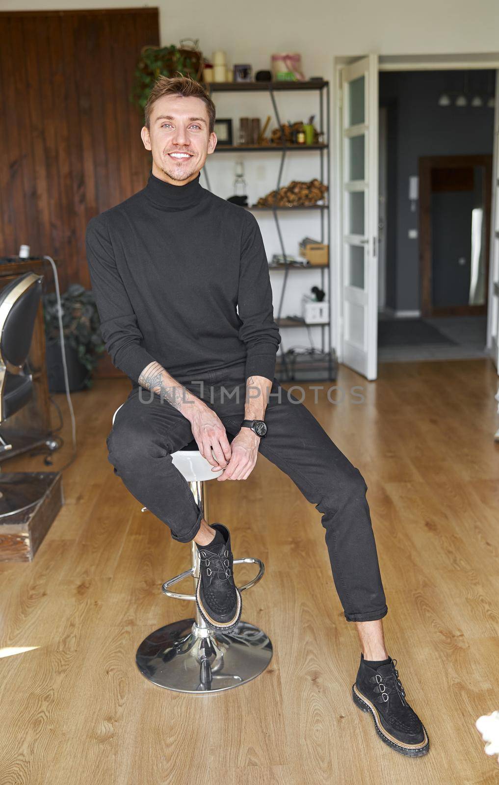 Male happy smiling hairdresser at his modern salon