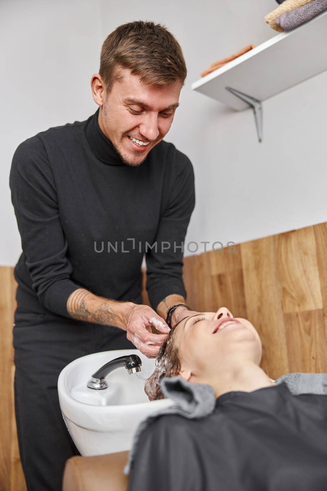 Confident stylist is washing hair of a beautiful caucasian female client at salon