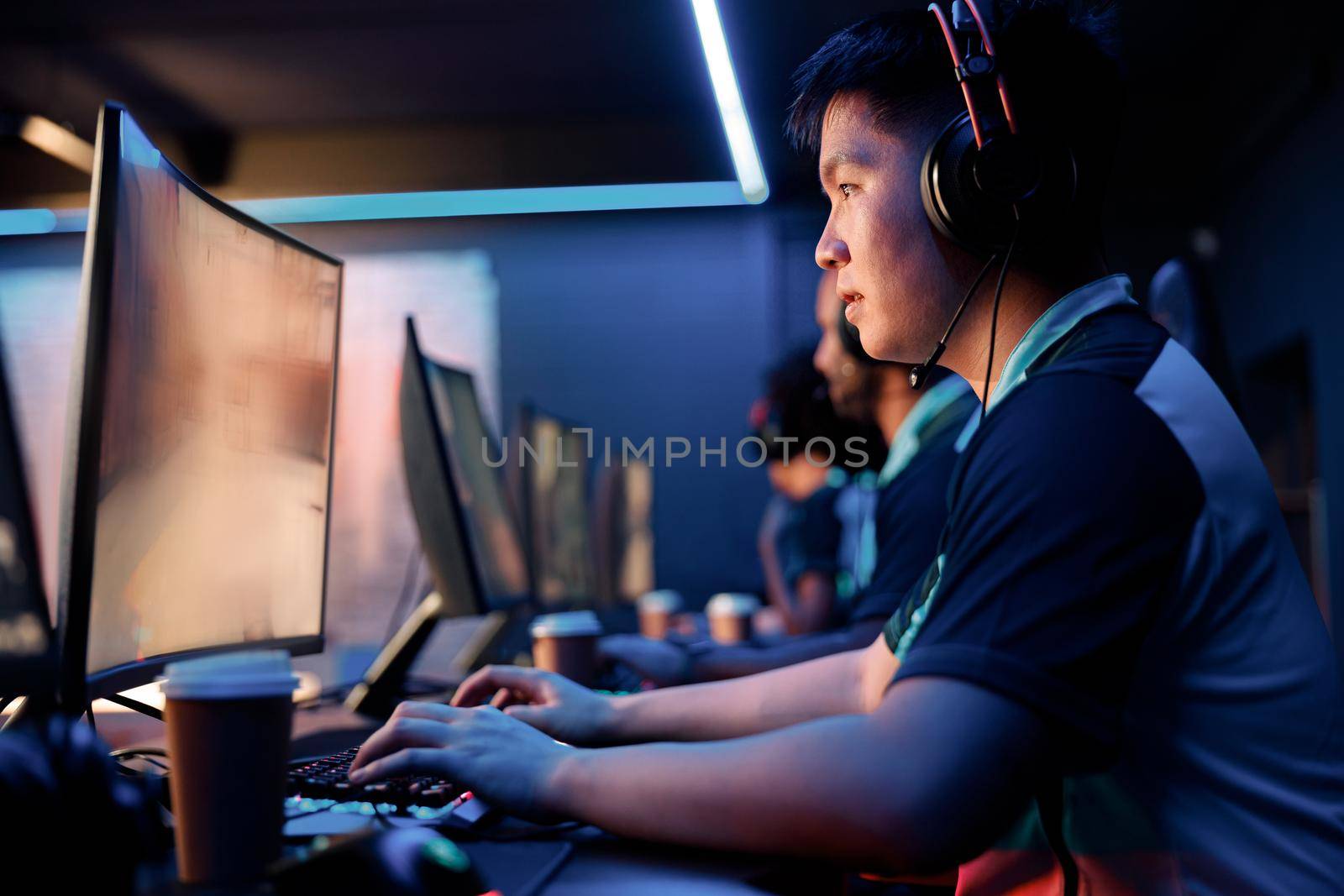 Asian esports player concentrated on game wearing modern headset while playing online multiplayer game in computer club