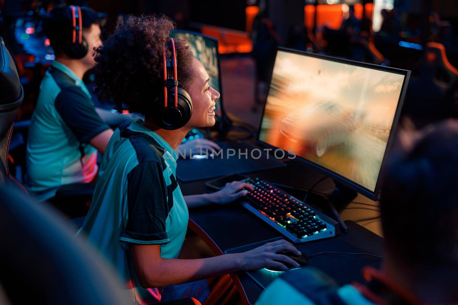 Happy African female esports gamer looking at PC monitor while practicing in online arena in contemporary e-sports club