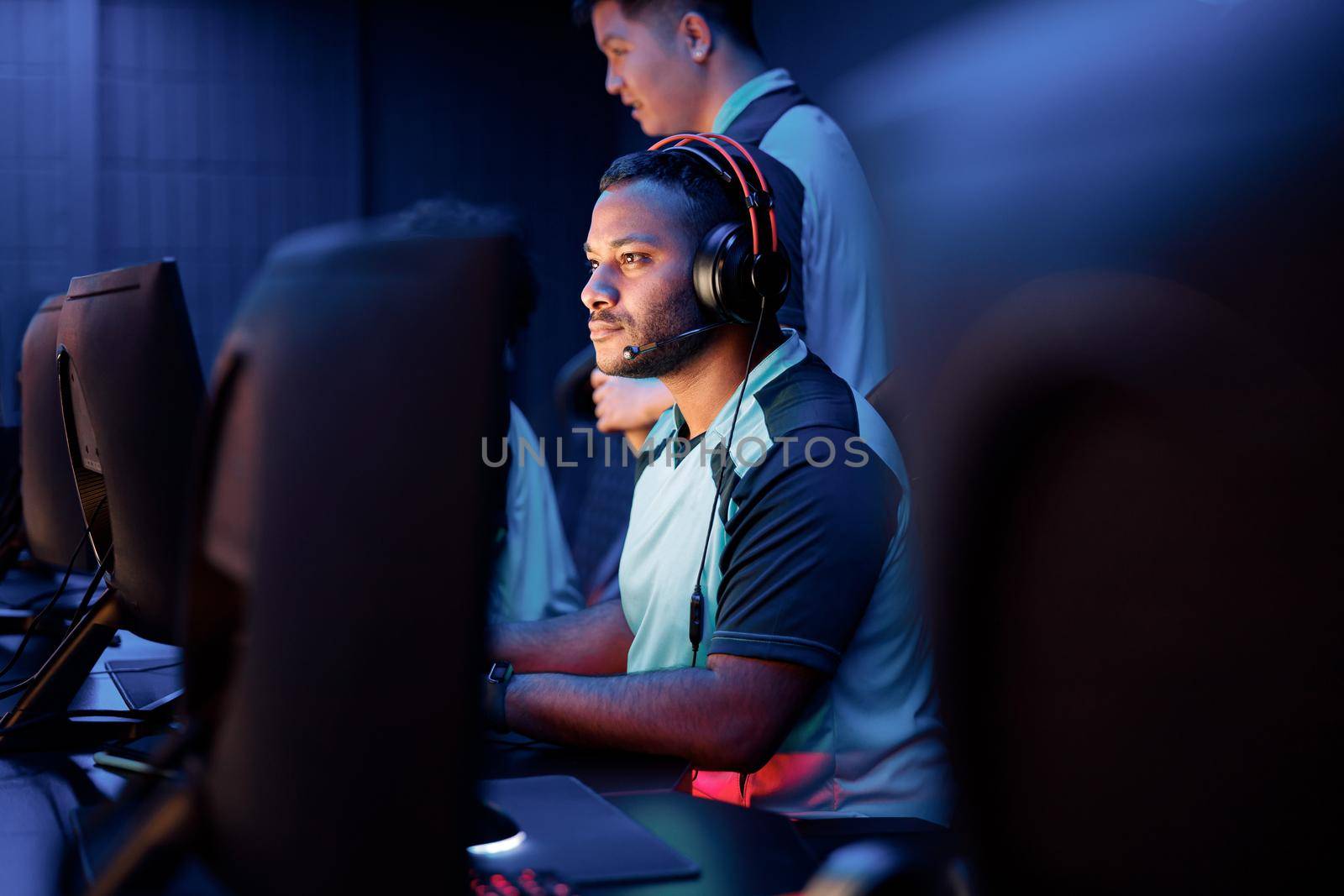 Focused African professional gamer participating in online cyber games tournament while sitting at pc gaming club
