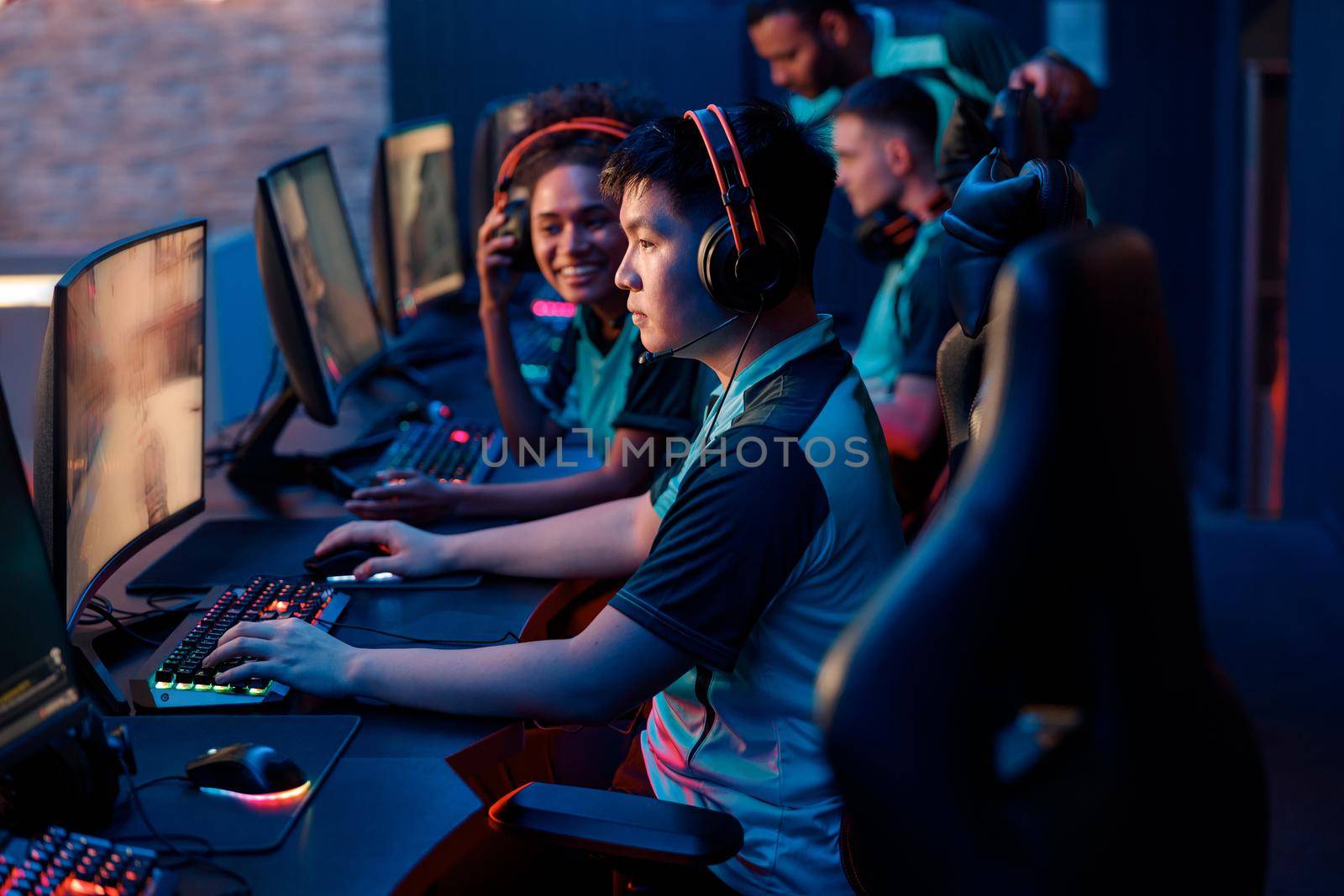 Side view of focused Asian man wearing headphones playing online video games while participating in esports tournament in gaming club