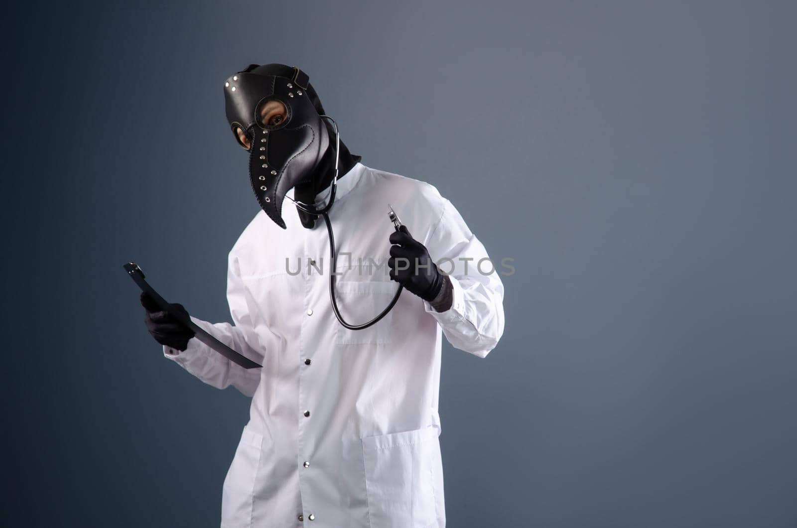 doctor in a dressing gown wearing a plague doctor mask with a stethoscope in his hands