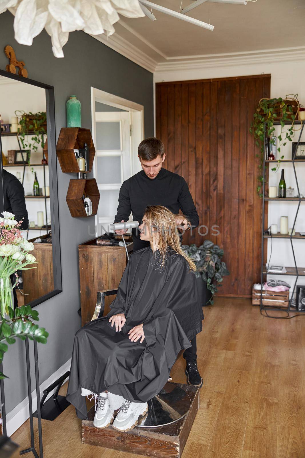 Happy beautiful light hair caucasian woman at beauty salon. Male master is drying her hair by Yaroslav_astakhov