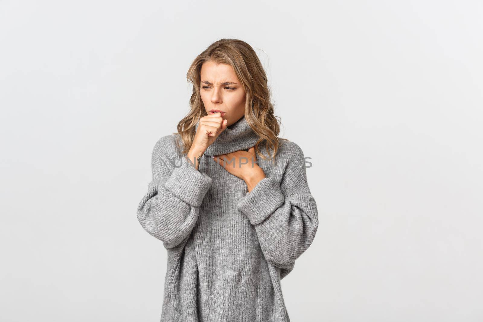 Image of sick woman in grey sweater, coughing and feeling unwell, standing over white background. Concept of health and covid-19 by Benzoix