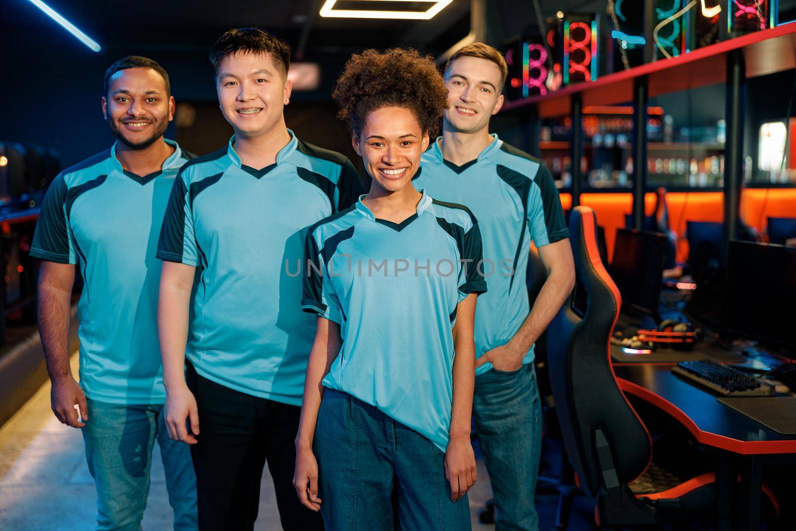 Team of four young multiracial professional cybersport gamers happy with their game while standing in contemporary e-sports club