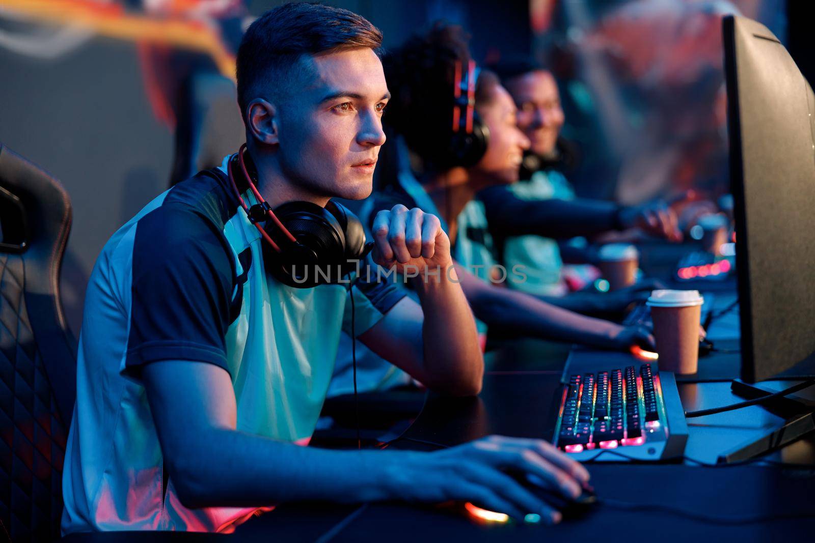 Horizontal shot of concentrated young gamer with headset playing in multiplayer video game on PC in gaming club
