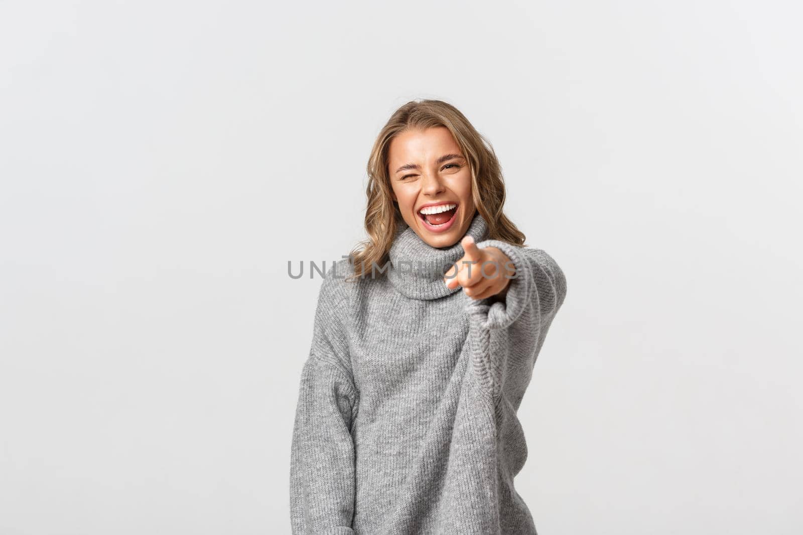 Attractive smiling woman in casual clothes pointing fingers at you, making her choice, standing over white background.