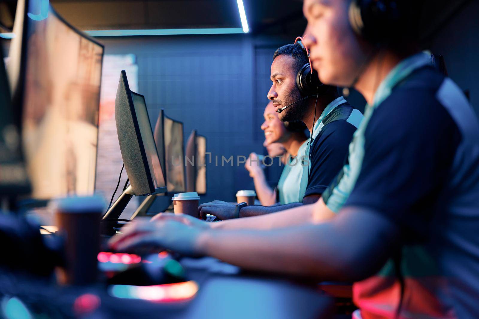 Selective focus on concentrated young man sitting together with esports players and playing video game in internet cafe