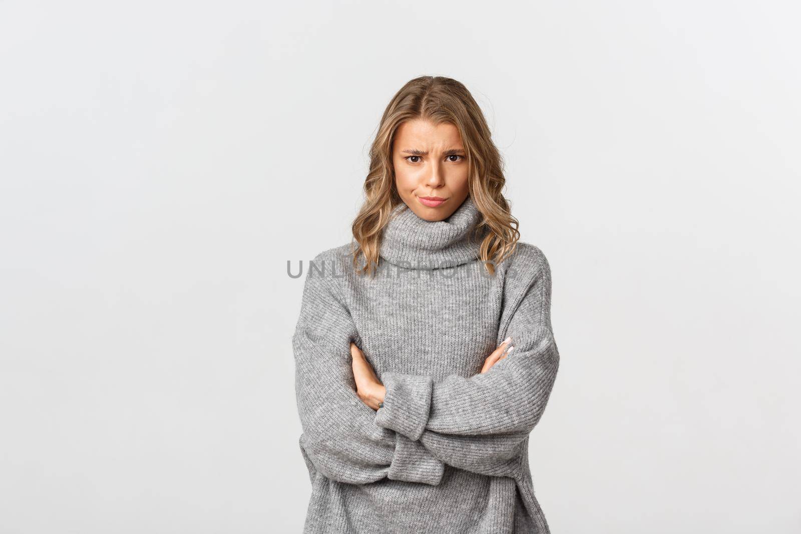 Image of disappointed gloomy girl, frowning and standing defensive, feeling offended or upset, standing over white background.