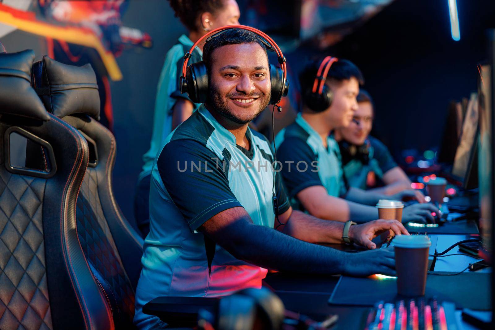 Professional cybersport gamer looking at camera and smiling while using powerful computer for online game in computer club