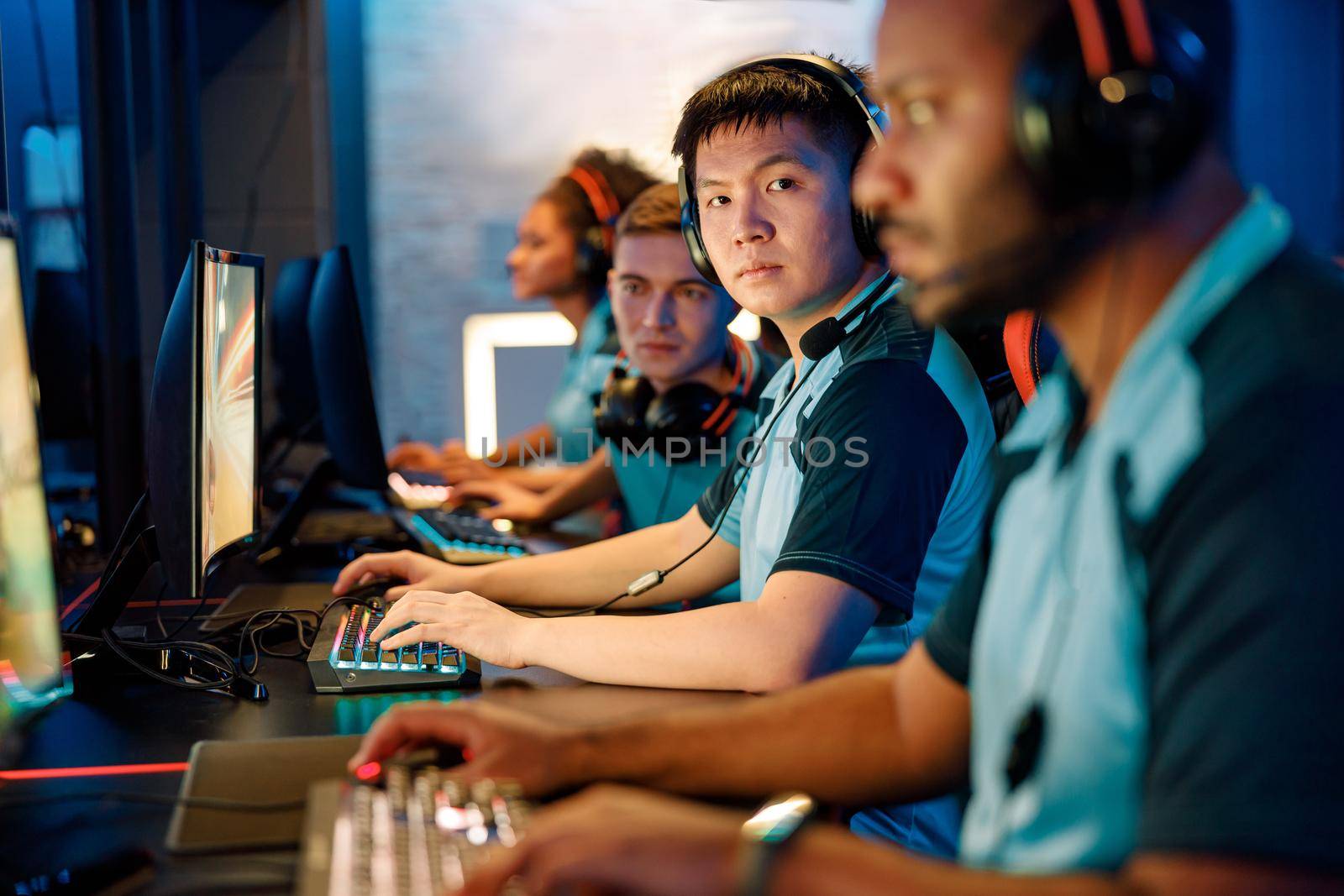 Asian professional cybersport gamer looking at camera with serious facial expression while participating in esports tournament in computer club