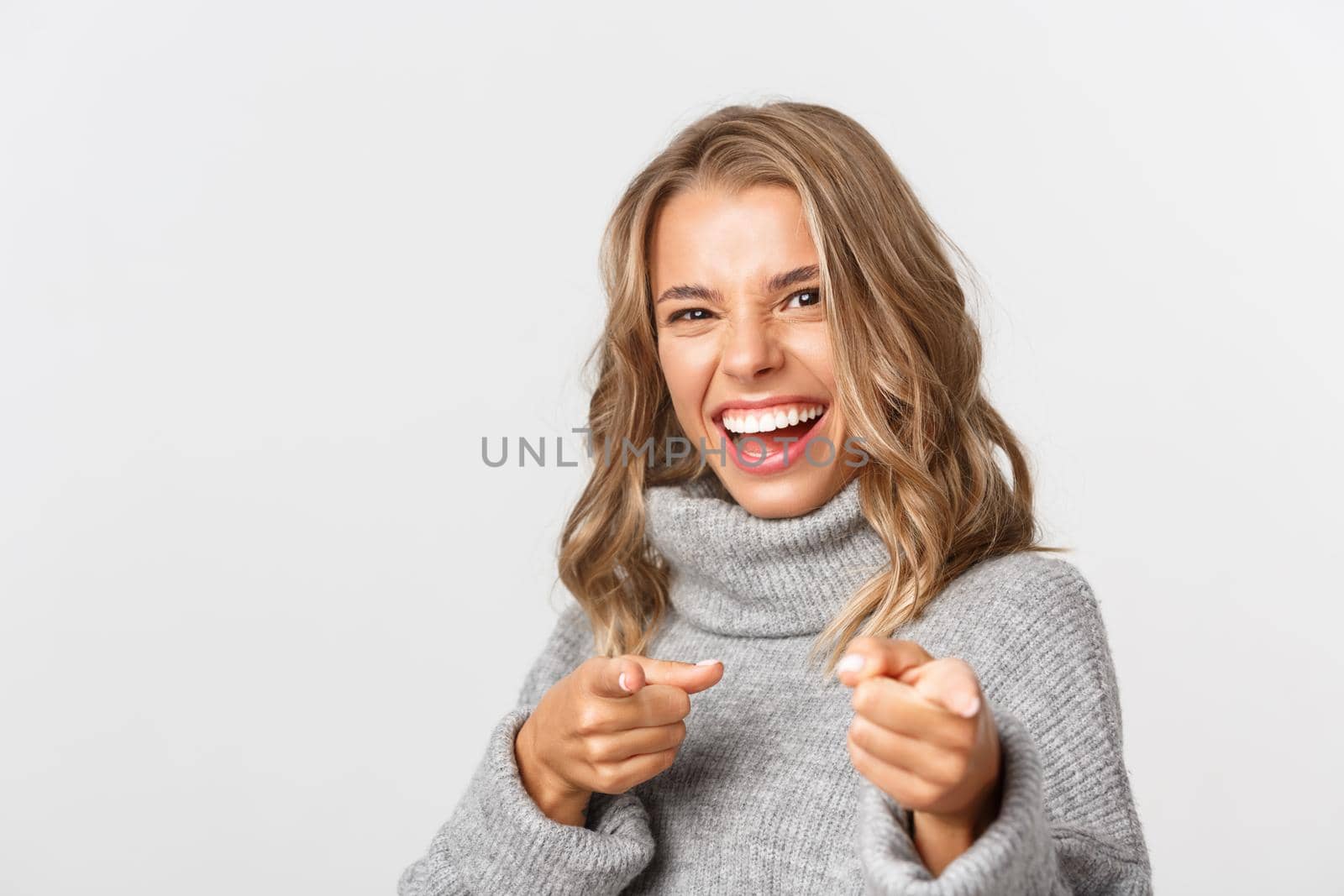 Close-up of cheerful pretty girl, pointing at camera and smiling, congratulating someone, need you, standing over white background.