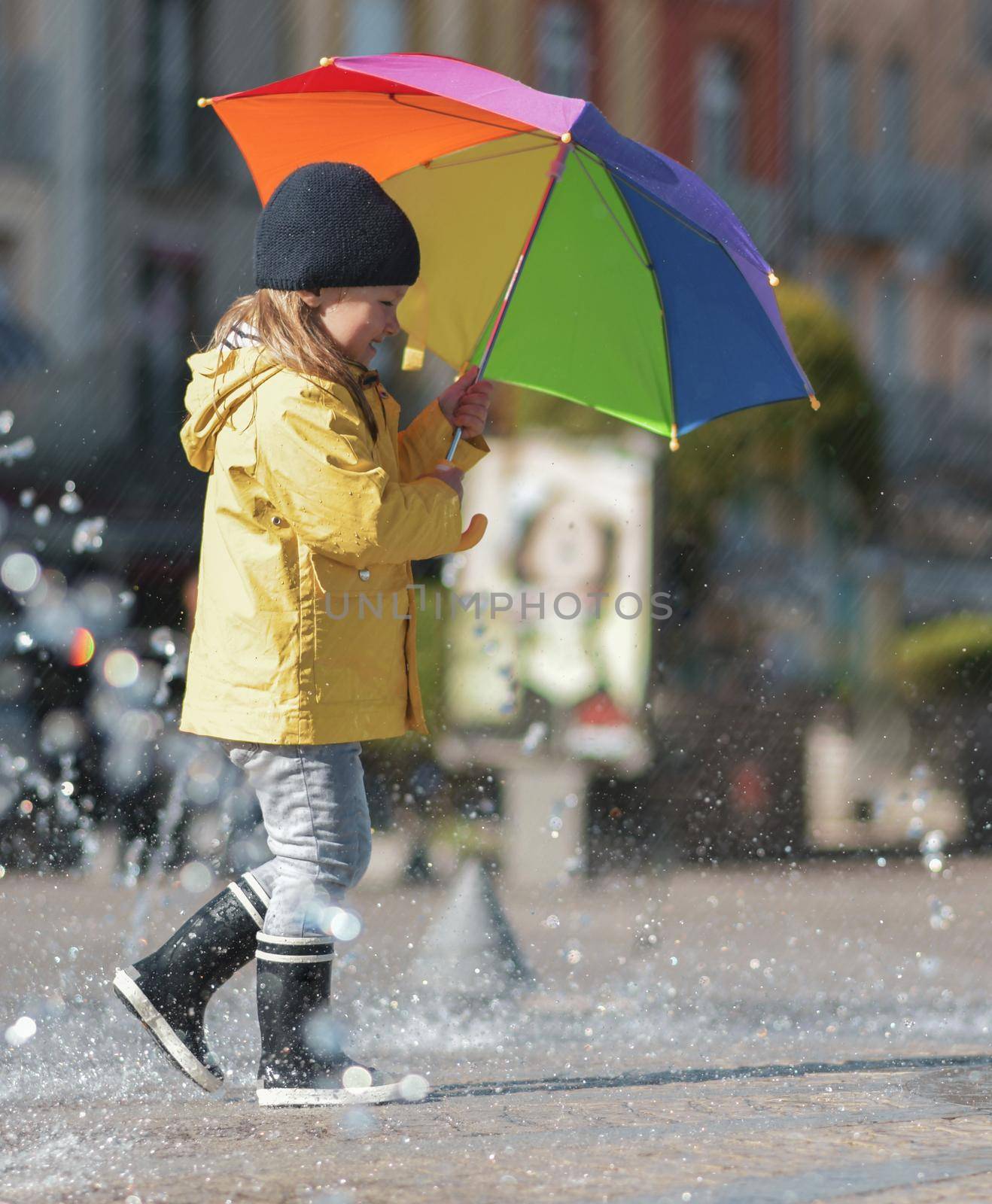 Girl in rubber boots running through the puddles