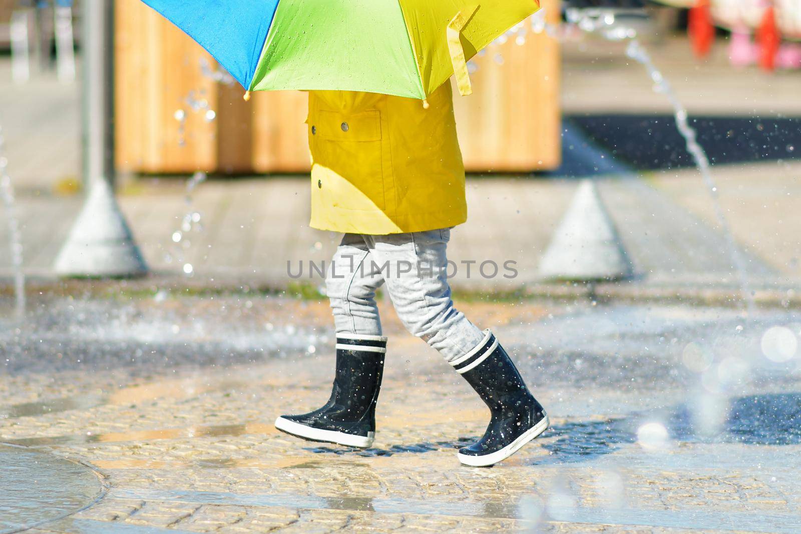 Girl in black rubber boots running through the puddles by Godi