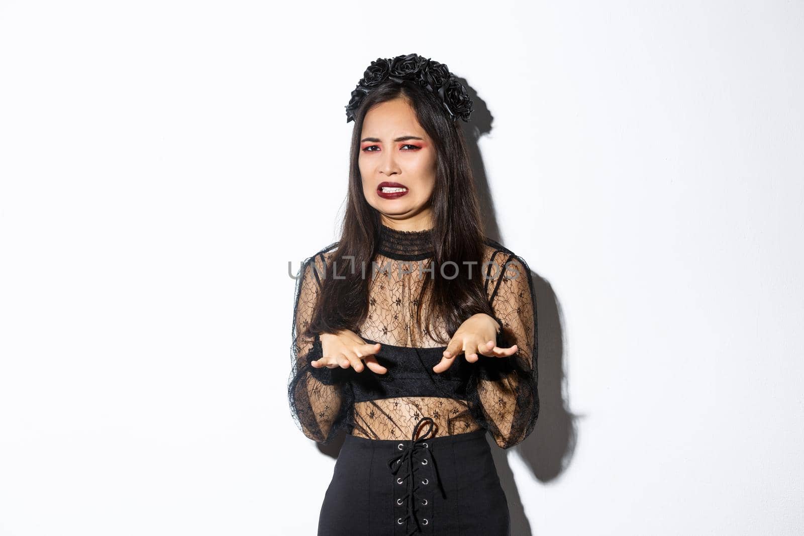 Image of funny asian woman in halloween witch costume looking disgusted, refuse from something nasty or creepy, standing over white background, express aversion by Benzoix