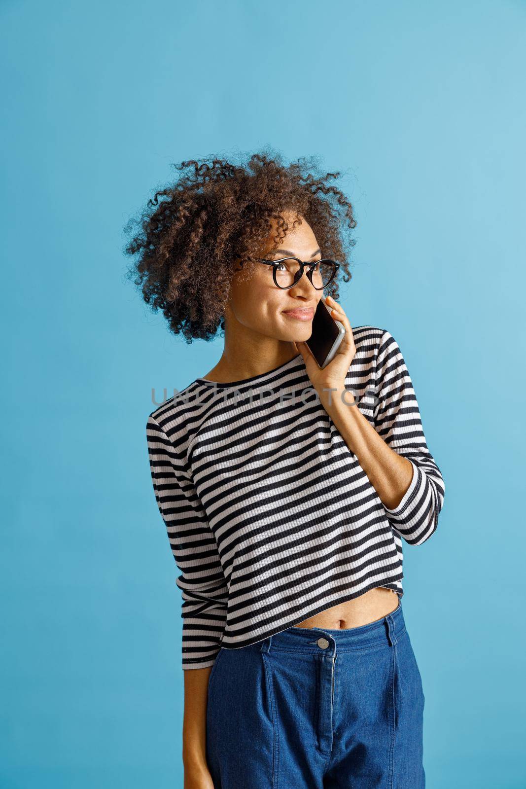 Multiracial lady having phone conversation and smiling. Isolated on blue background