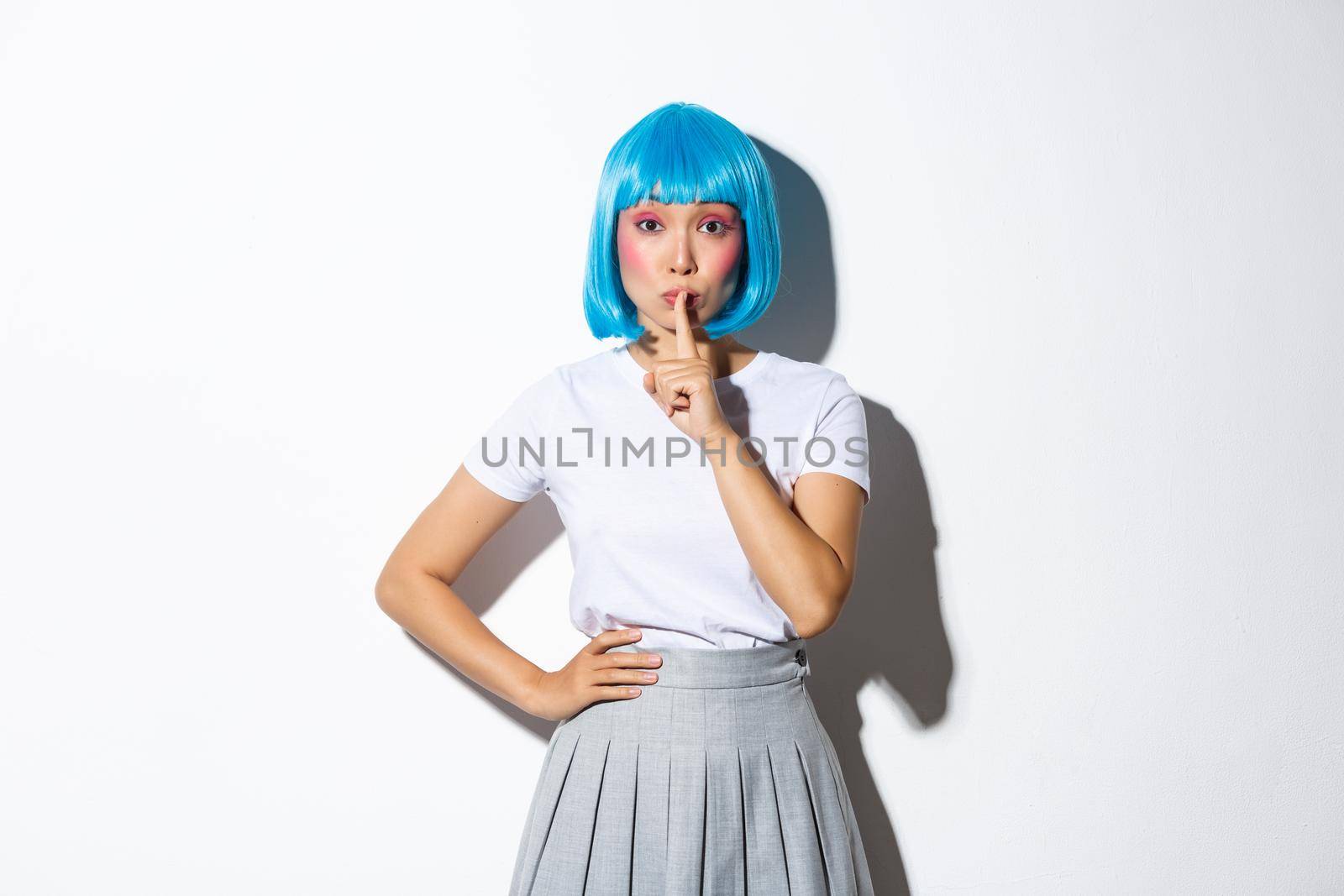 Image of silly beautiful asian girl in blue short wig and kawaii makeup, shushing at camera as if sharing a secret, hushing while standing over white background by Benzoix