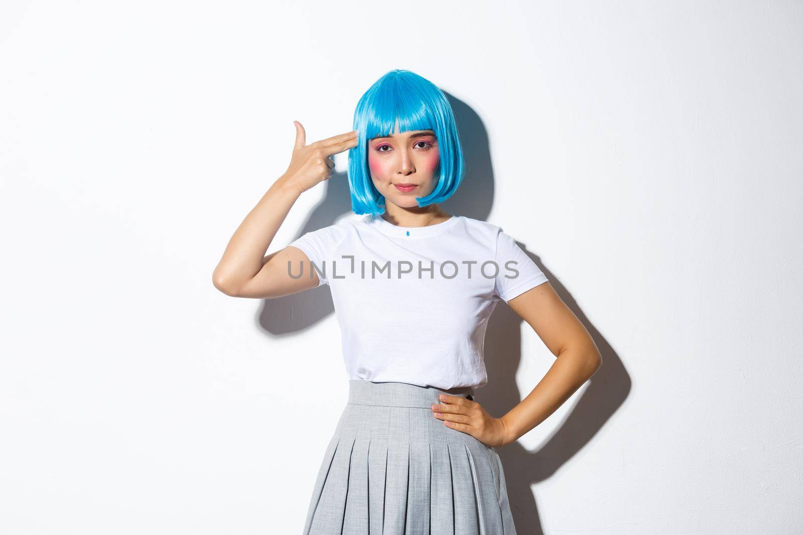 Image of bothered asian woman looking unamused while pointing hand gun at her head, wearing blue wig for halloween party, standing over white background by Benzoix