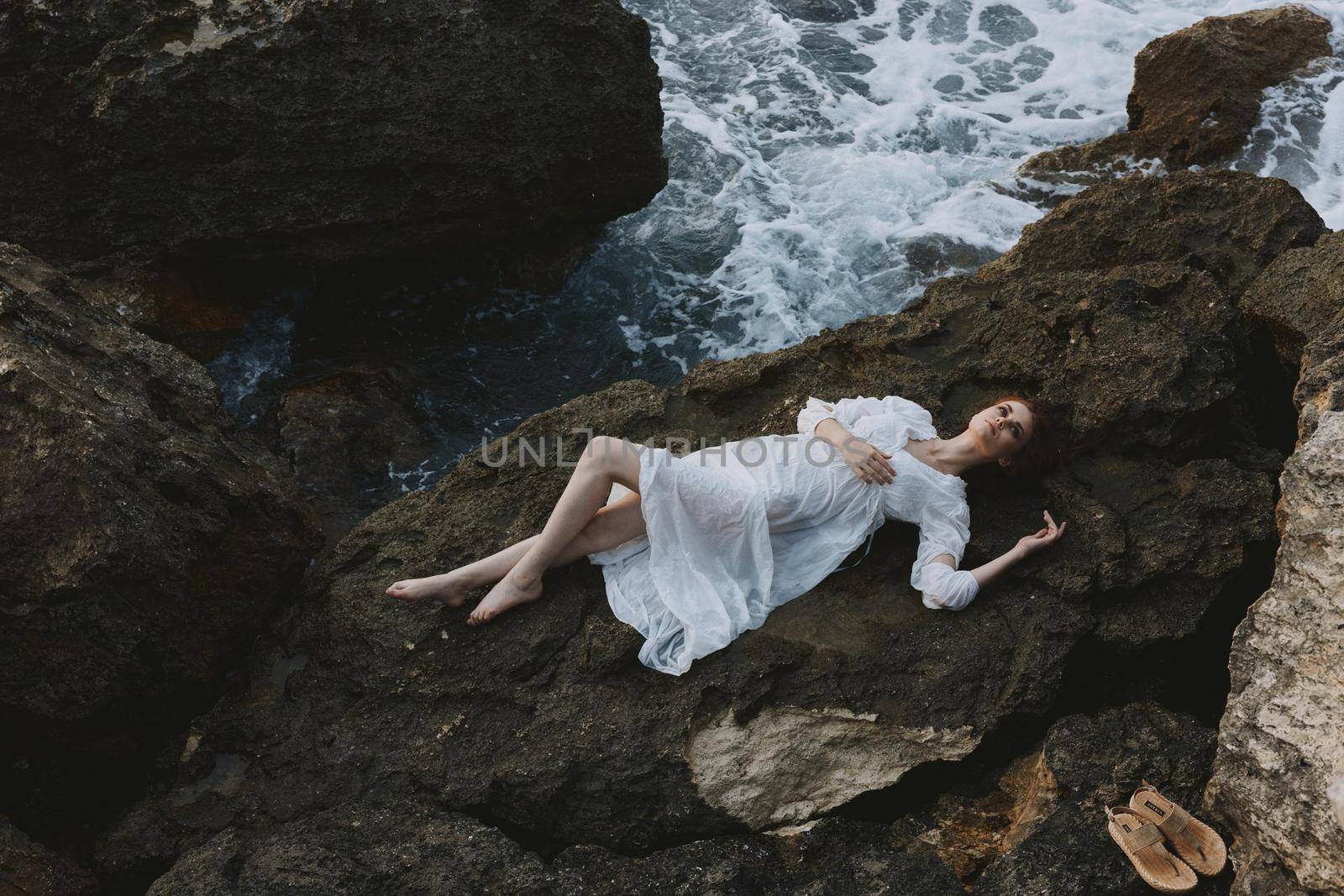 Beautiful bride in a secluded spot on a wild rocky coast in a white dress unaltered. High quality photo