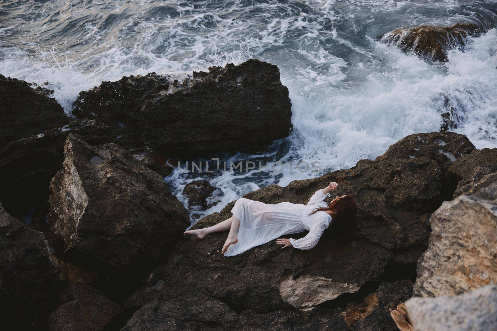 Barefoot woman in white wedding dress on sea shore wet hair view from above. High quality photo