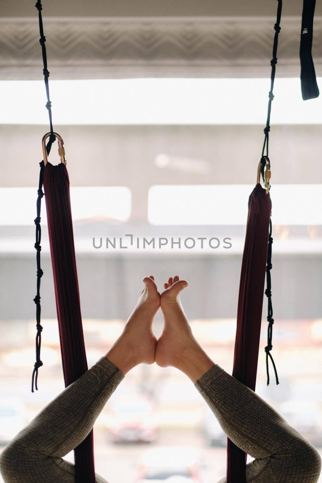Close-up of the legs of a girl hanging on a hanging hammock and doing yoga in the gym.