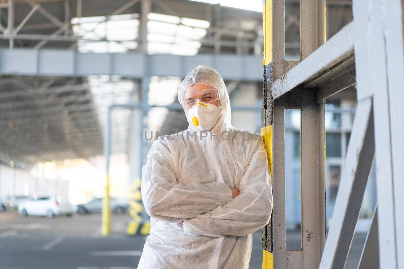 COVID-19 coronavirus doctor standing hospital parking dressed white protective overalls hazmat suit. Infectious disease pandemic medical worker front line, outbreak. Male medical worker medium shoot