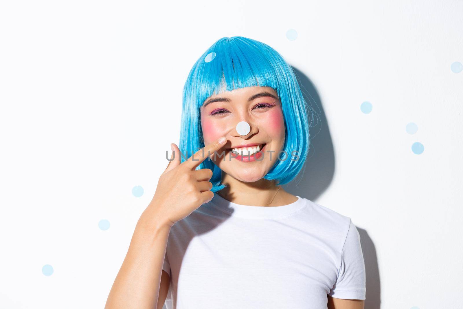 Image of cute and silly asian girl with confetti on her nose smiling and looking happy, wearing blue wig for halloween party by Benzoix