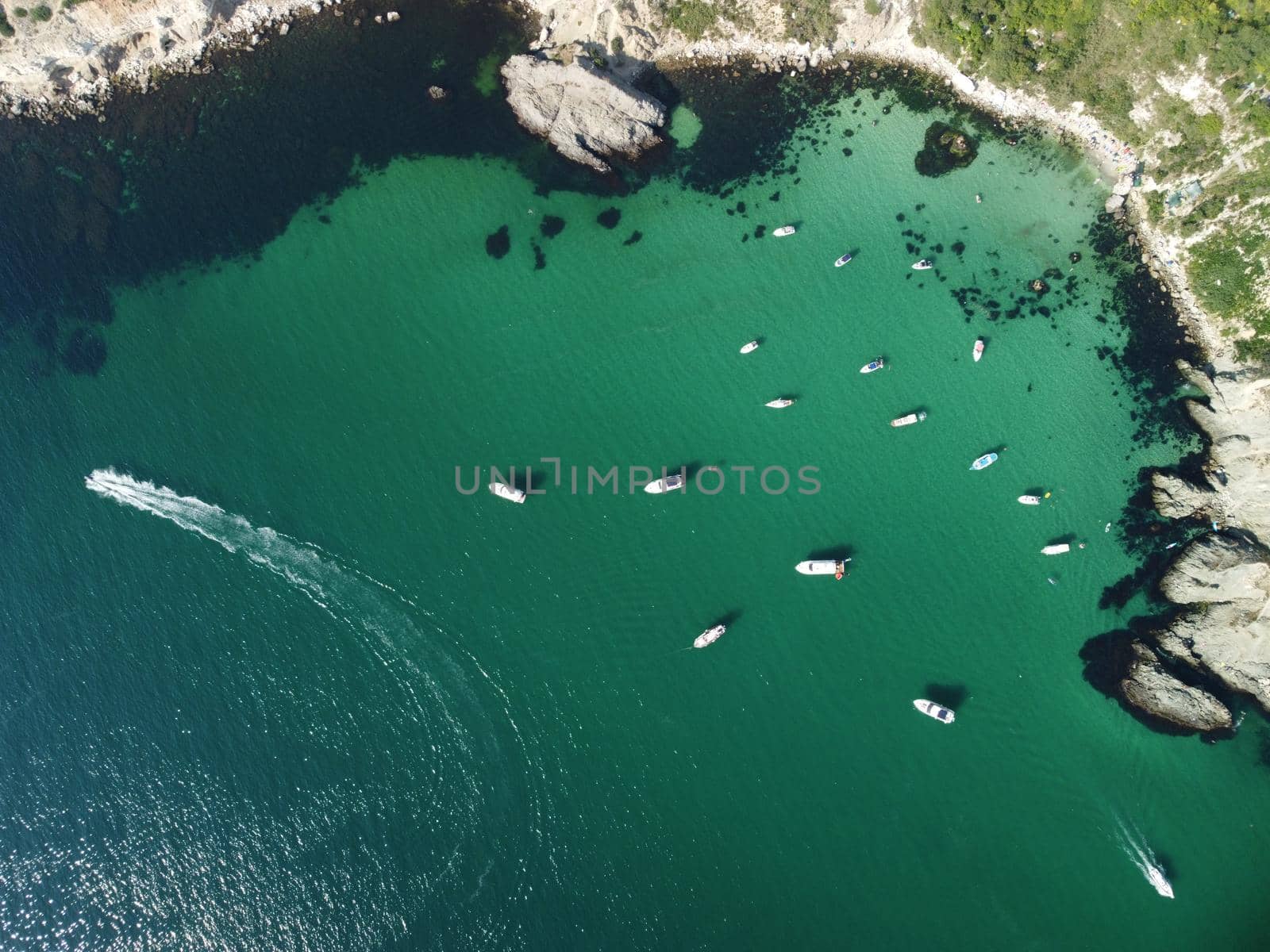 Sea landscape with rocky coastline on sunset time with cloudy sky. Yachts in the Sea on a background of rocky shores. The concept of perfect place for summer travel and rest.