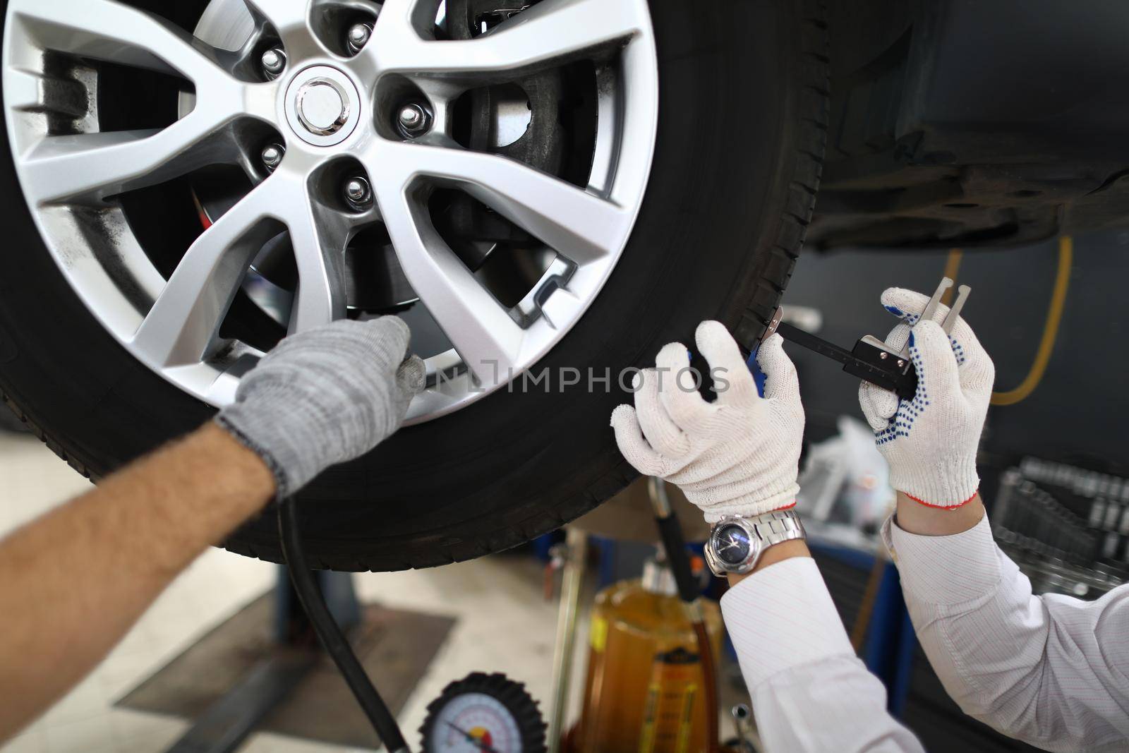 Men repairmen fixing car on lift in workshop closeup by kuprevich