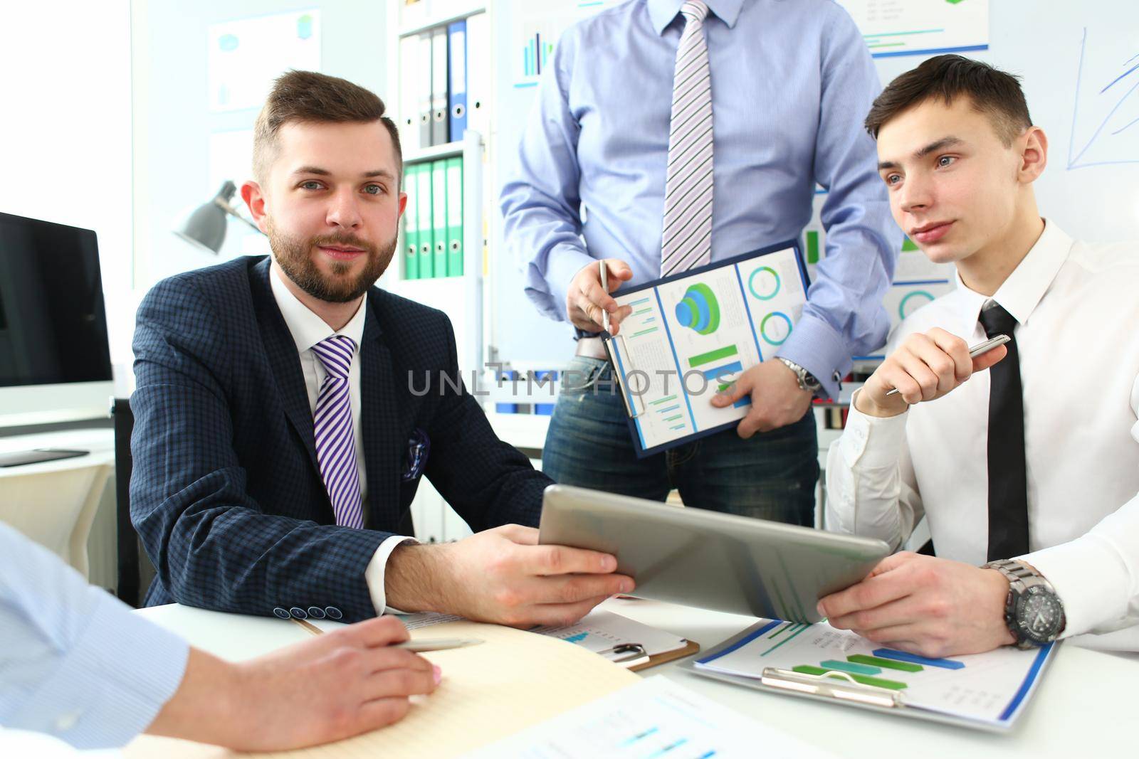 Group of business people discussing charts on paper and digital tablet by kuprevich