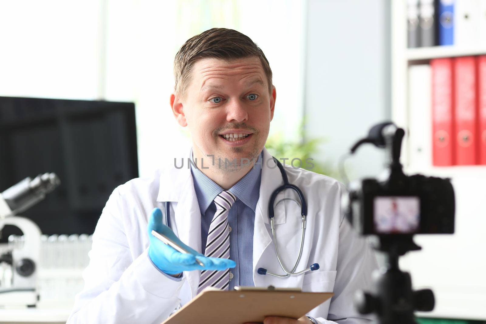 Male doctor speaking into camera in clinic. Medical blogging concept