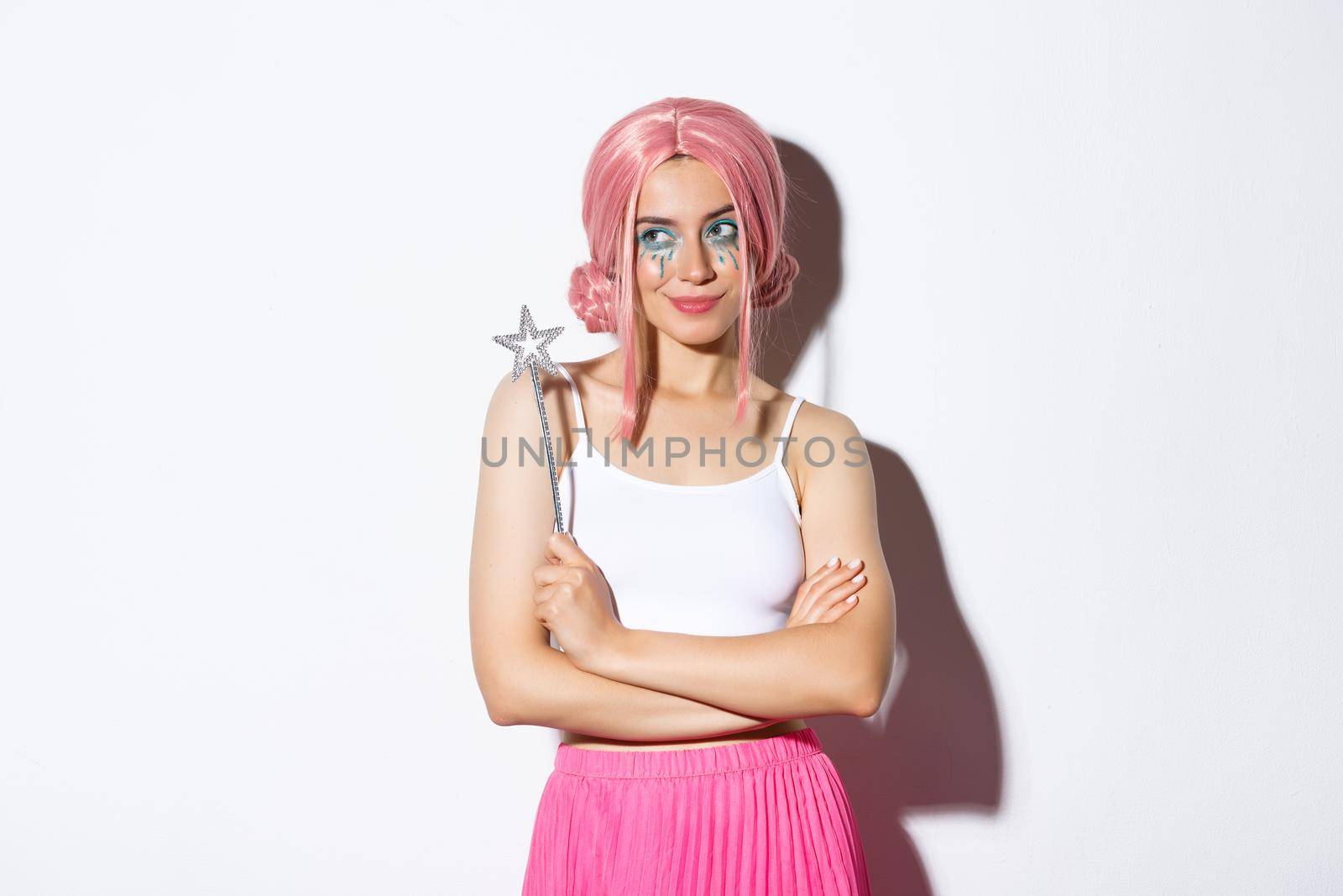 Image of beautiful girl dressed as a fairy in pink wig, holding magic wand and smiling, celebrating halloween.