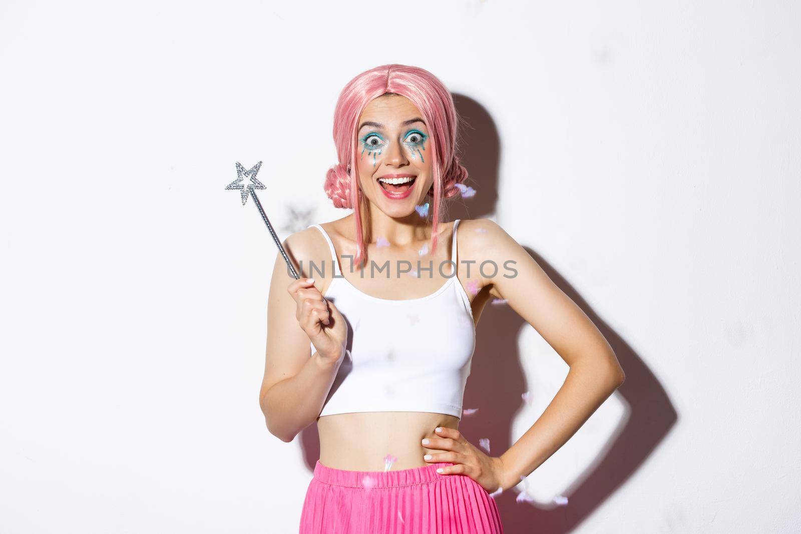 Portrait of happy girl smiling, celebrating halloween in fairy costume, with pink wig and bright makeup, holding magic wand, looking excited by Benzoix