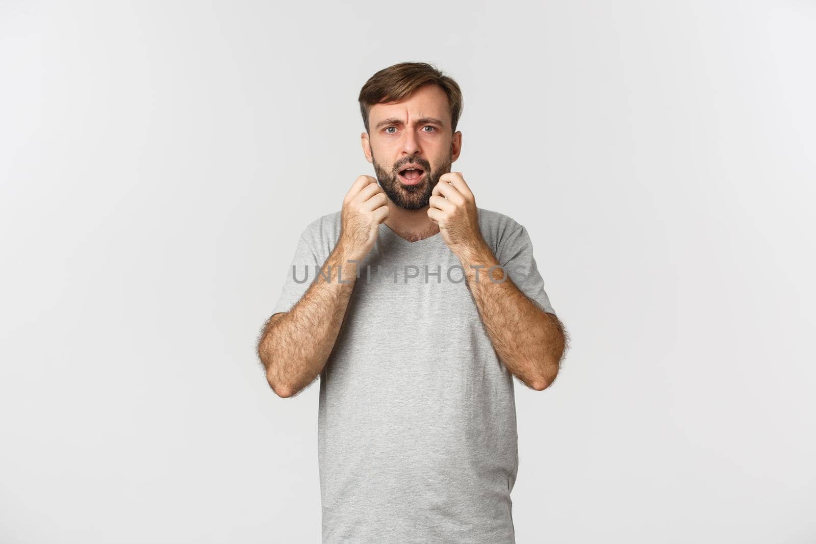 Portrait of horrified and shocked man grimacing, standing anxious over white background.