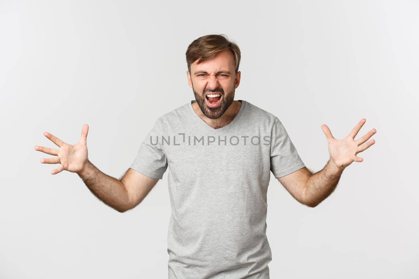 Portrait of angry bearded man, shouting and shaking hands frustrated, standing mad over white background.