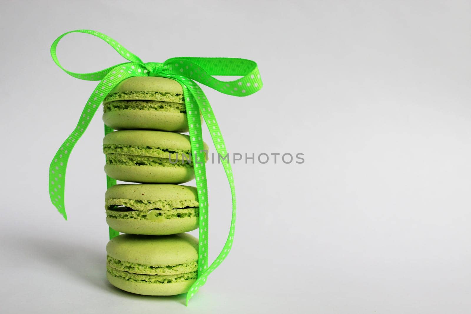 Green macaroon cakes with a light green ribbon on a white background. Nice design for any purpose. White background. Surprise for the holiday.